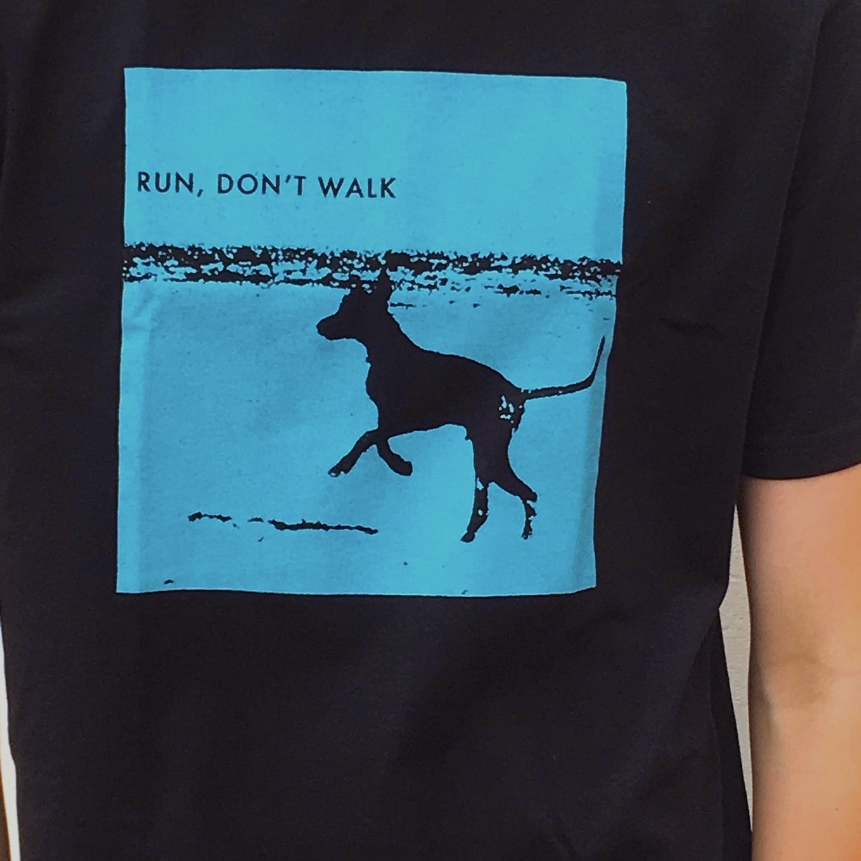 Photograph of screenprinted t-shirt depicting a prancing dog at Leighton Beach, Western Australia.