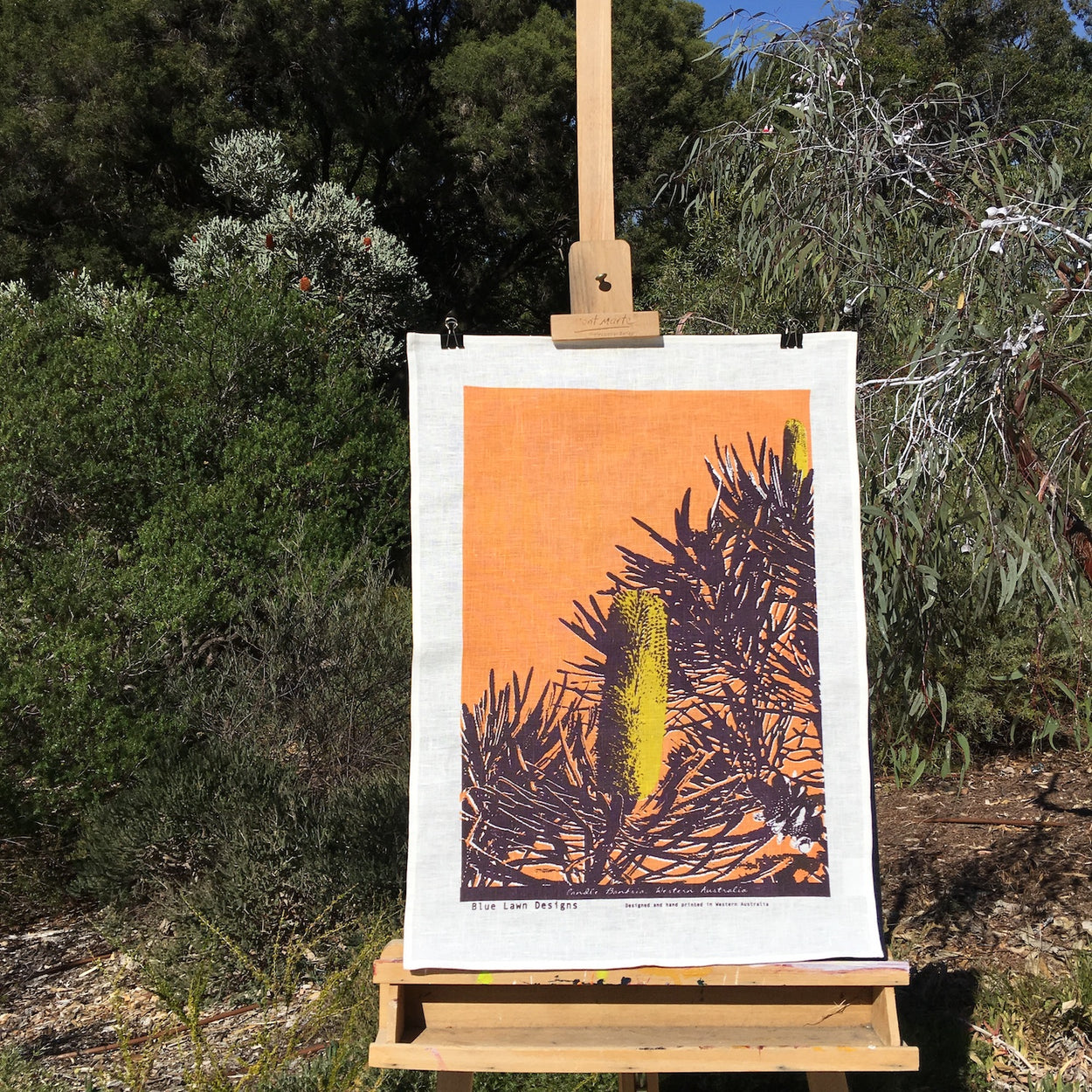Photograph of a candle banksia tea towel on an easel in the bush.