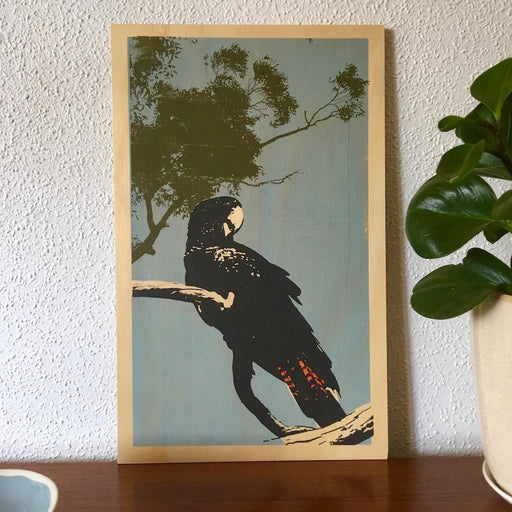 Photo of a red-tailed black cockatoo screenprinted on plywood. 