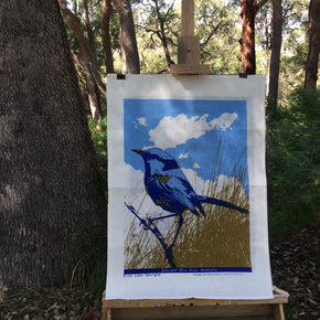 Photo of a Splendid Blue Fairywren on an easel in a forest setting.